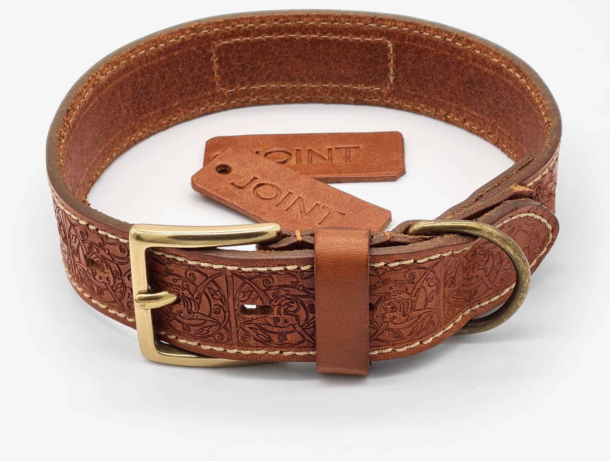 Ein Hundehalsband aus hochwertigem Leder. Das Leder des Halsbandes ist hellbraun und mitieinem Muster geprägt. In der Mitte liegen zwei passende handgefertigte Hundemarken (Dogtags).