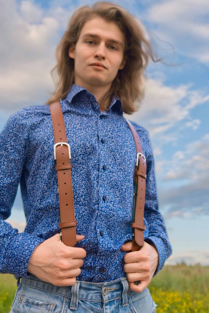 Mann mit braunem Lederhosenträger von Hepco. Er steht auf einer Wiese.