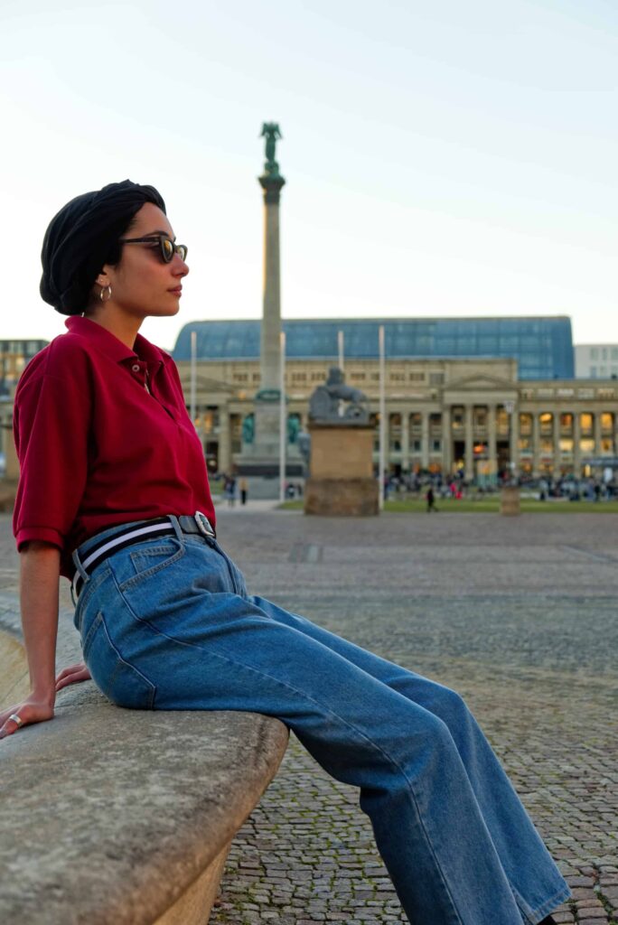Gürtel für Stuttgart — Diese Frau trägt einen Gürtel. Sie sitzt entspannt in der Stuttgarter Innenstadt auf dem Schlossplatz, vor dem Königsblau und der Siegessäule.
