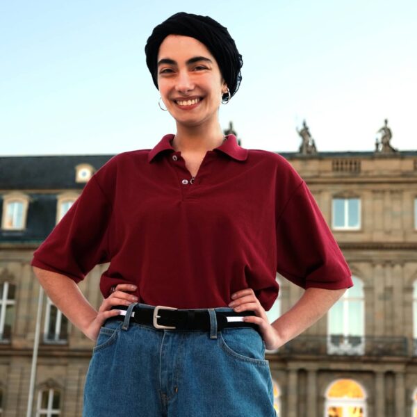 Frau mit einem auf der Hüfte getragenen Bandgürtel von Hepco. Der Gürtel ist schwarz-weiß gestreift. Die Frau steht vor dem Neuen Schloss in Stuttgart.