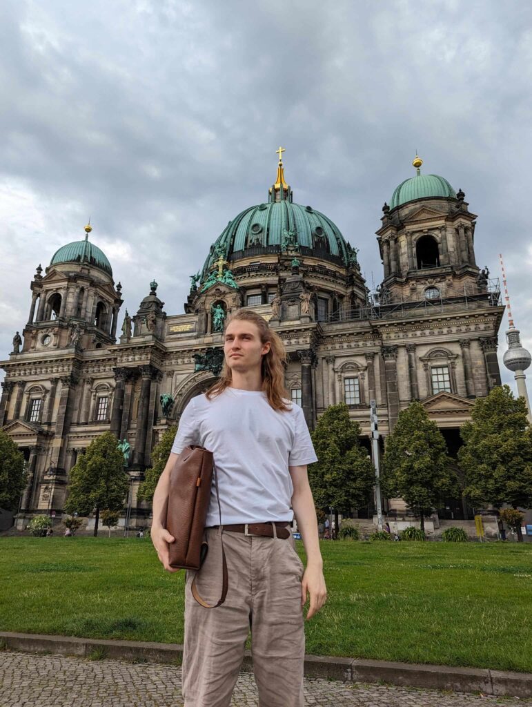 Eine junger Mann steht in Berlin mit Gürtel Lederrucksack der Marke Hepco vor dem Berliner Dom auf der Museumsinsel in Berlin.